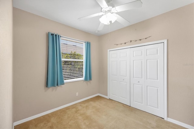 unfurnished bedroom featuring a closet, ceiling fan, light carpet, and baseboards