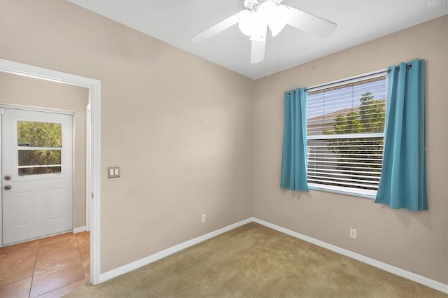 spare room with a ceiling fan, light carpet, and baseboards