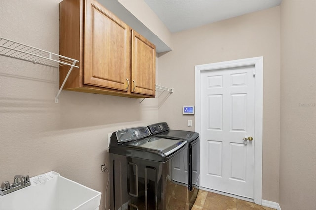 washroom with baseboards, a sink, cabinet space, and independent washer and dryer