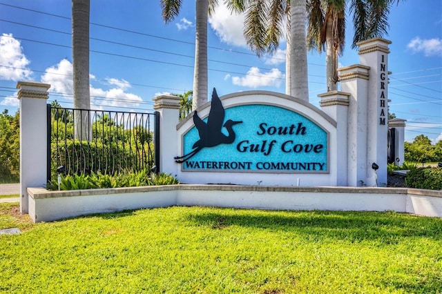 community / neighborhood sign featuring fence and a lawn