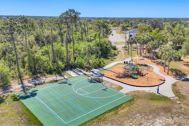 view of sport court with playground community, a wooded view, and community basketball court