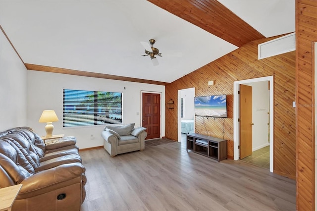 living room with light wood-style floors, wooden walls, a ceiling fan, vaulted ceiling, and baseboards