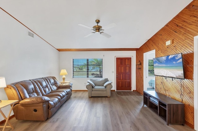 living area featuring ceiling fan, wooden walls, visible vents, light wood-style flooring, and baseboards