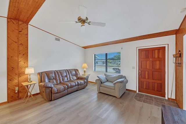 living area featuring light wood-style floors, a ceiling fan, visible vents, vaulted ceiling, and baseboards
