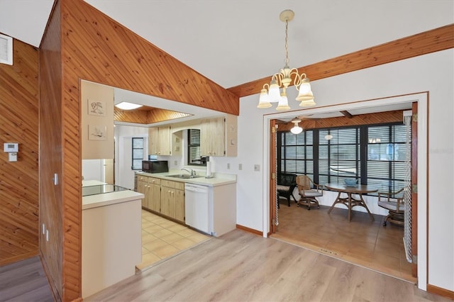 kitchen with light countertops, dishwasher, a sink, a notable chandelier, and wooden walls