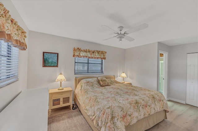 bedroom with light wood finished floors, ceiling fan, and baseboards