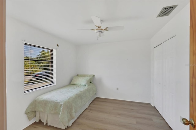 bedroom with visible vents, ceiling fan, baseboards, a closet, and wood finished floors