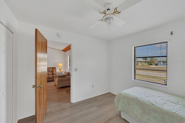bedroom with ceiling fan, light wood-style flooring, and baseboards