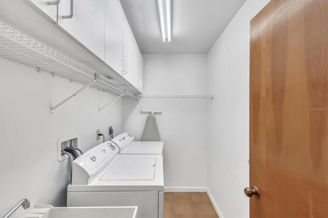 clothes washing area with light tile patterned floors, cabinet space, washing machine and clothes dryer, and baseboards