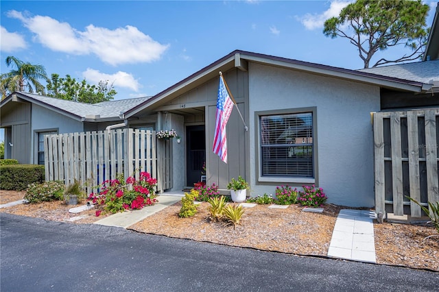 ranch-style house featuring fence and stucco siding