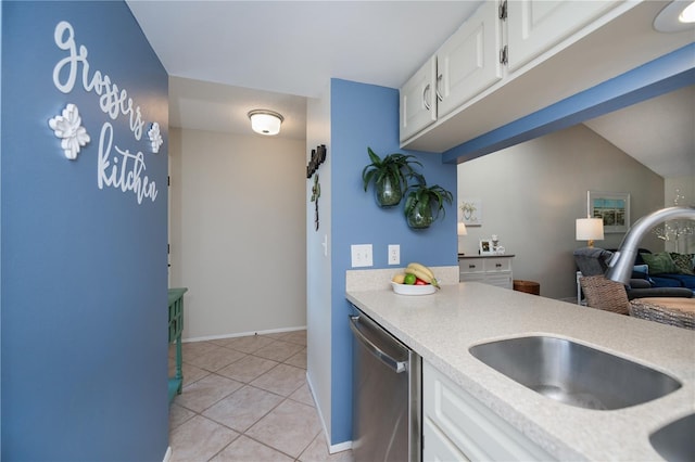 kitchen featuring white cabinets, stainless steel dishwasher, light tile patterned floors, and light countertops