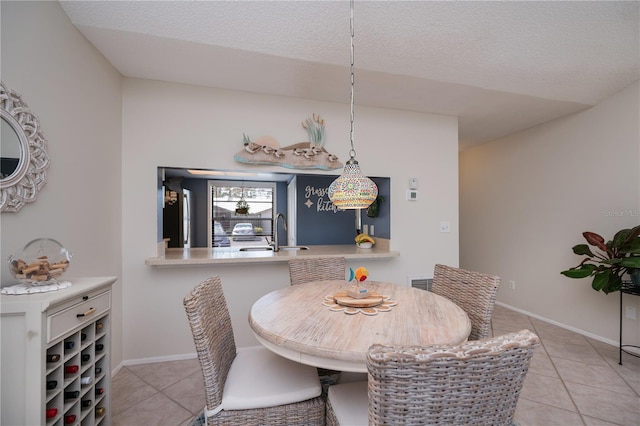 dining area featuring a textured ceiling, baseboards, and light tile patterned floors