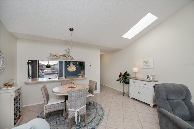 dining area with a textured ceiling, light tile patterned floors, and vaulted ceiling with skylight