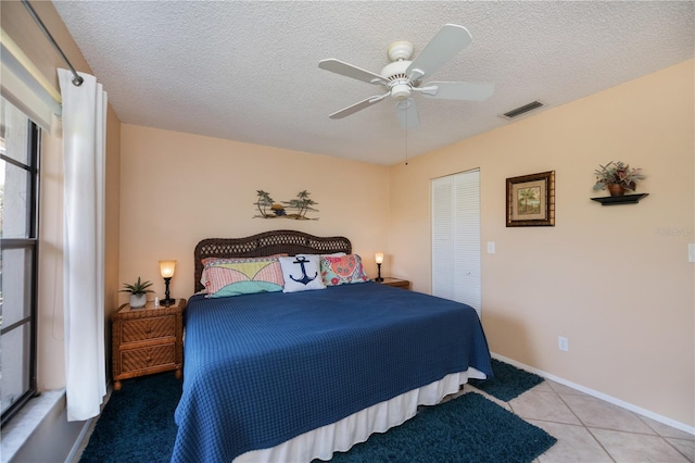 bedroom featuring a textured ceiling, a closet, ceiling fan, baseboards, and visible vents