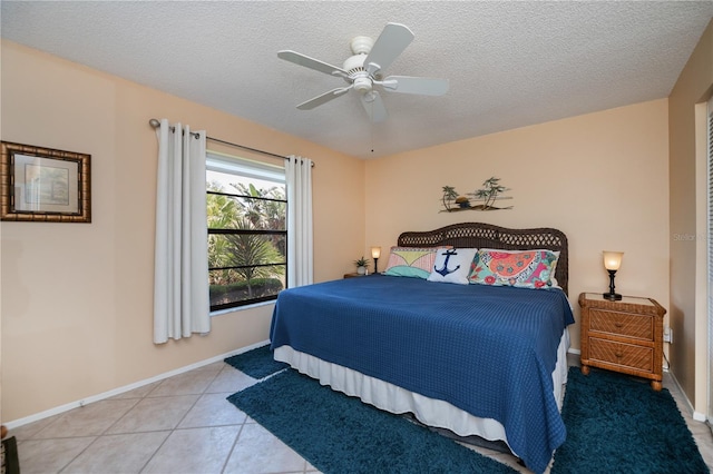 bedroom featuring ceiling fan, baseboards, tile patterned flooring, and a textured ceiling