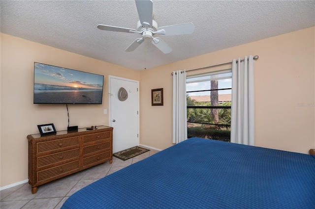 bedroom with a ceiling fan, baseboards, a textured ceiling, and light tile patterned flooring