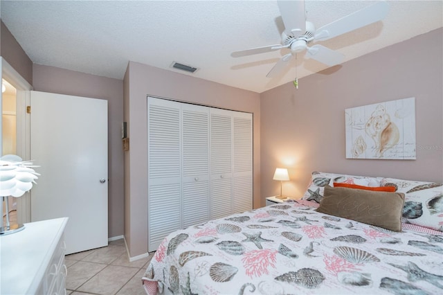 bedroom with ceiling fan, light tile patterned flooring, visible vents, and a closet