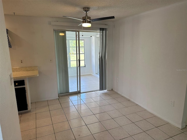 194 Garden Ave NW, Port Charlotte, FL 33952 - unfurnished dining area with light tile patterned flooring, a textured ceiling, a ceiling fan, and baseboards