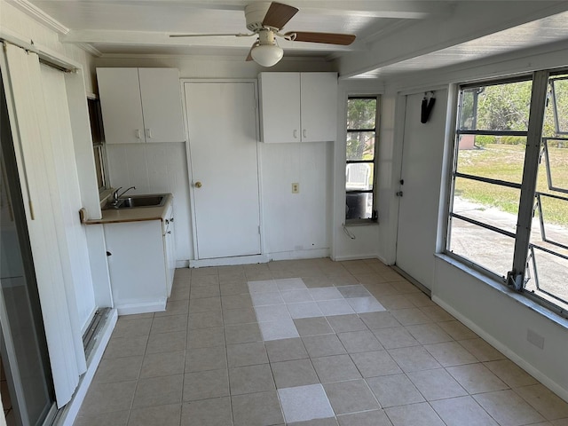 194 Garden Ave NW, Port Charlotte, FL 33952 - kitchen with white cabinets, a sink, beamed ceiling, a ceiling fan, and light tile patterned floors