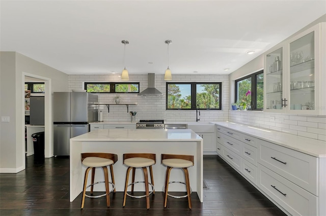 kitchen featuring backsplash, stainless steel appliances, a sink, and wall chimney exhaust hood