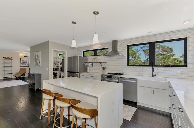 kitchen featuring stainless steel appliances, light stone counters, wall chimney exhaust hood, and tasteful backsplash