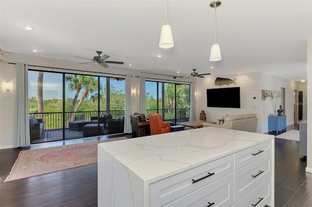 kitchen with light stone countertops, open floor plan, ceiling fan, dark wood-type flooring, and white cabinets