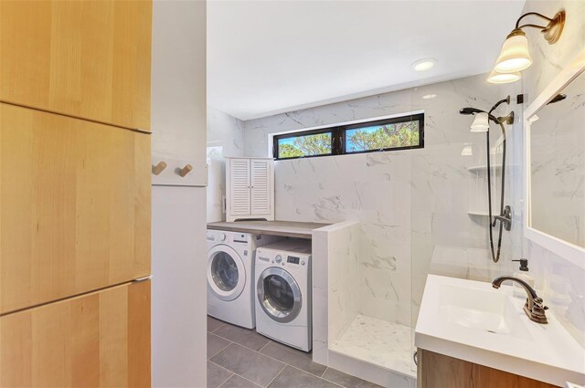 clothes washing area with a sink, independent washer and dryer, and dark tile patterned flooring