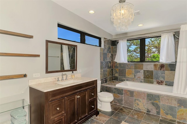 bathroom featuring vanity, recessed lighting, tiled tub, stone finish flooring, and a notable chandelier