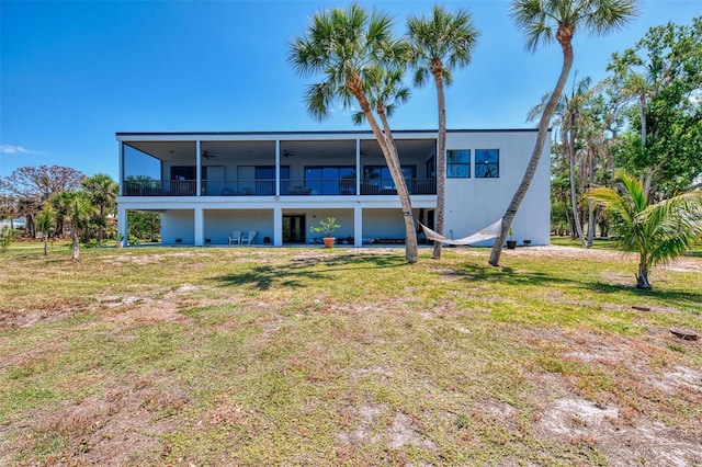 back of property with a yard, ceiling fan, a sunroom, and stucco siding