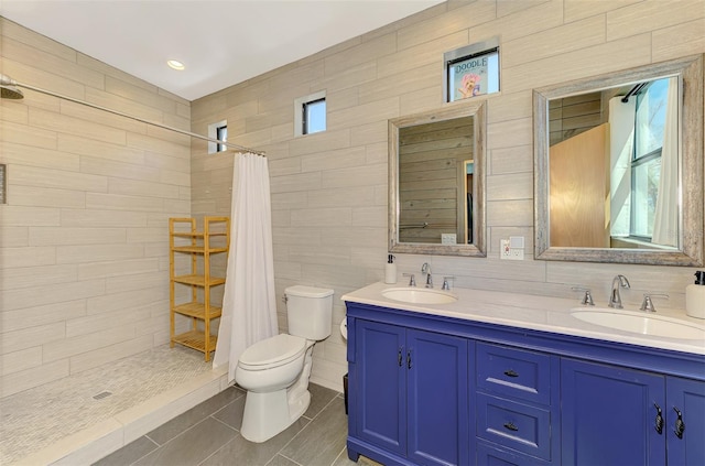 full bath featuring double vanity, a sink, toilet, and tiled shower