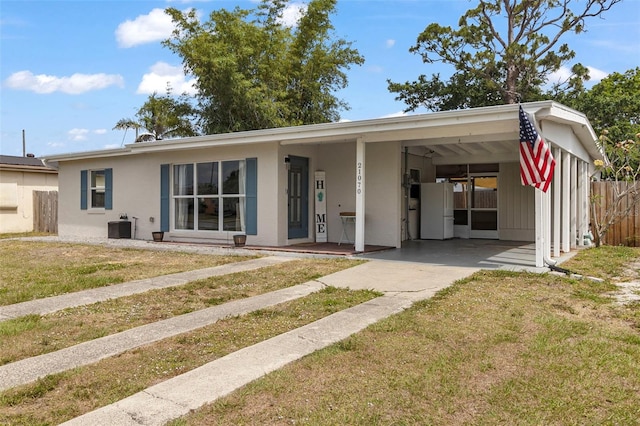 rear view of property featuring an attached carport, fence, concrete driveway, a yard, and stucco siding