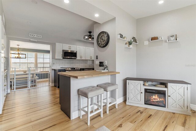 kitchen featuring light wood-type flooring, stainless steel appliances, wood counters, and a breakfast bar