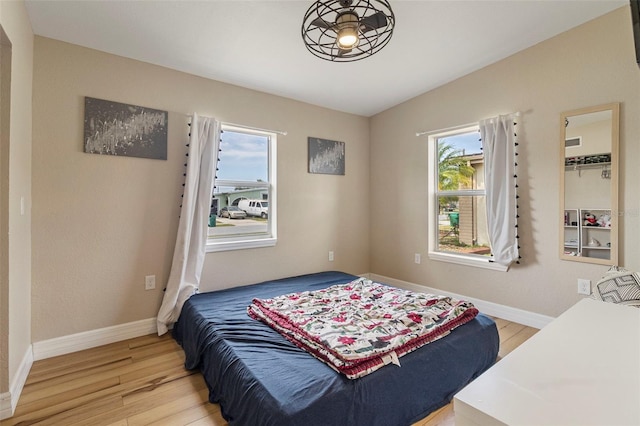 bedroom with baseboards, lofted ceiling, and light wood-type flooring