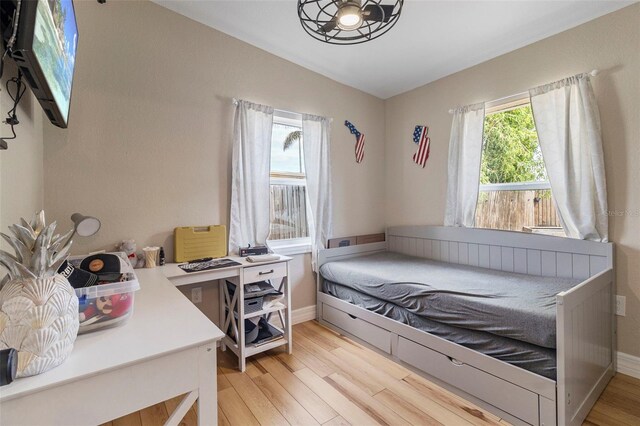 bedroom featuring vaulted ceiling, baseboards, and light wood-style floors