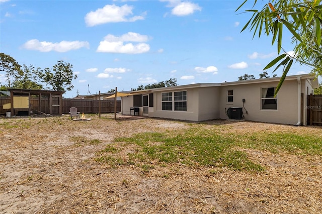 rear view of house with central air condition unit, a fenced backyard, and stucco siding