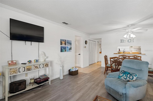 1531 Placida Rd Unit 201, Englewood, FL 34223 - living area with wood finished floors, a textured ceiling, ceiling fan, ornamental molding, and visible vents