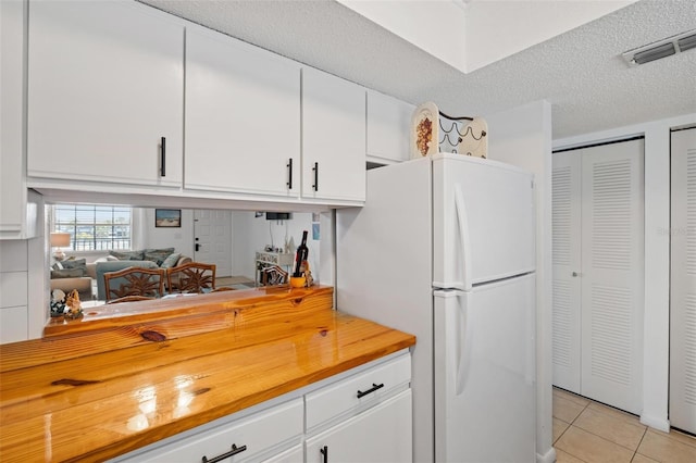 1531 Placida Rd Unit 201, Englewood, FL 34223 - kitchen with wooden counters, light tile patterned floors, white cabinets, visible vents, and freestanding refrigerator