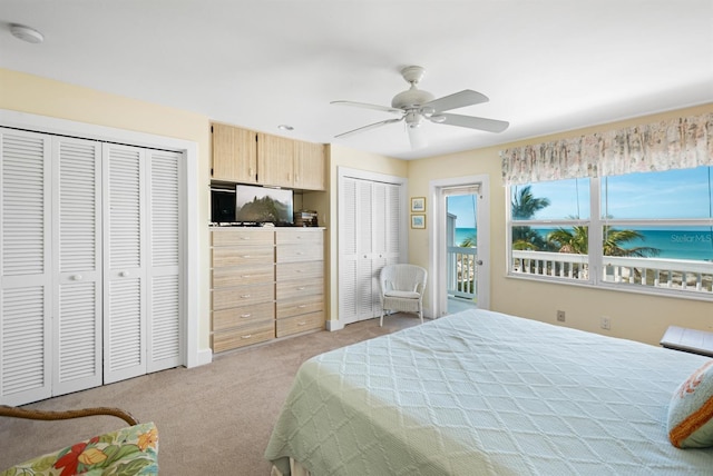 bedroom featuring light carpet, two closets, and ceiling fan