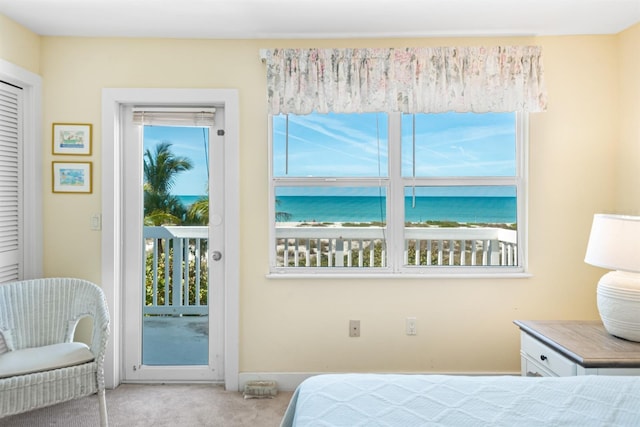 carpeted bedroom with a water view and access to outside