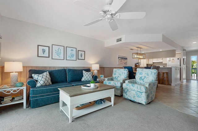 carpeted living room featuring ceiling fan with notable chandelier, wainscoting, wooden walls, visible vents, and recessed lighting