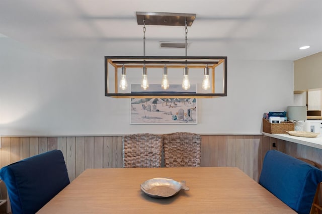 dining room featuring visible vents, a wainscoted wall, and wood walls