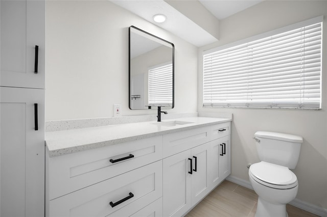 bathroom featuring toilet, vanity, and baseboards
