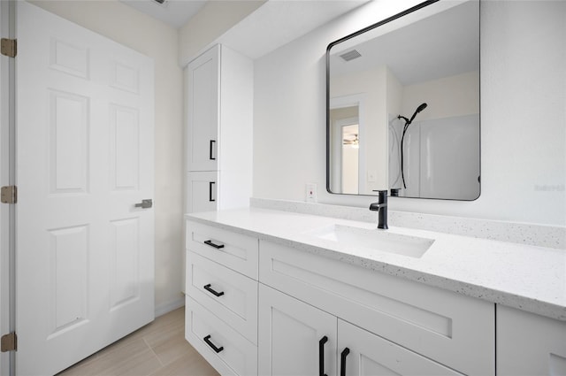 bathroom with a shower, wood finished floors, visible vents, and vanity
