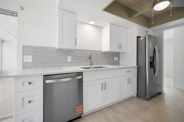 kitchen featuring appliances with stainless steel finishes, white cabinetry, tasteful backsplash, and a sink