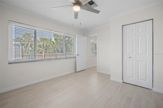 unfurnished bedroom with light wood-style flooring, a closet, ornamental molding, baseboards, and visible vents