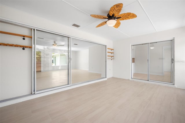 spare room with wood finished floors, visible vents, and a ceiling fan