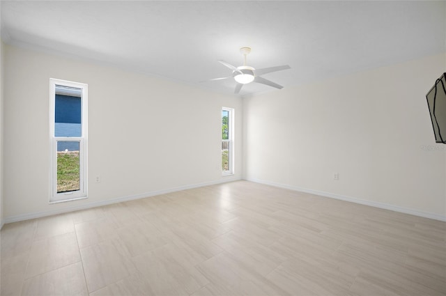 unfurnished room with ceiling fan and baseboards