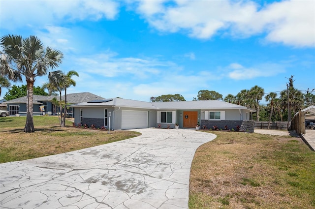 ranch-style home with roof mounted solar panels, a front yard, an attached garage, and fence