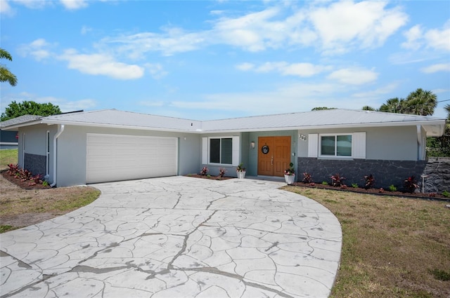 single story home featuring concrete driveway, stone siding, an attached garage, stucco siding, and a front lawn