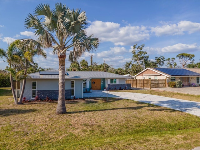 ranch-style house featuring a front lawn, driveway, solar panels, and stucco siding